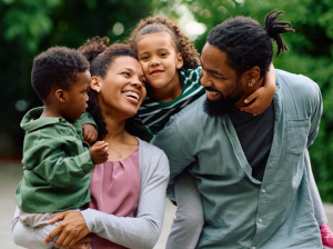 Happy African American parents spending time with their small kids outdoors