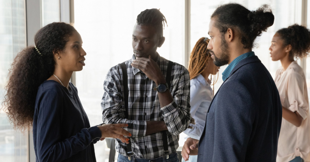 African American colleagues chatting, sharing ideas, standing in office stock photo